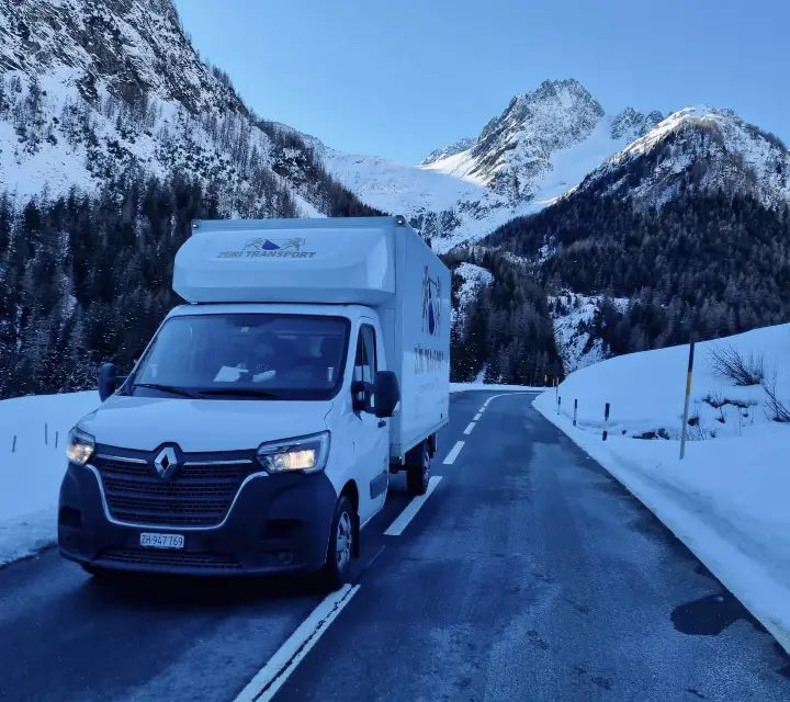 Umzugswagen von Züri Transport auf einer Alpenstrasse im Schnee